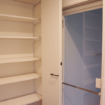 脱衣所には大きな収納。クリーンなガラスのお風呂へのドア。