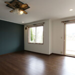 海辺の山々を望む開放的なリビングルーム。1壁を落ち着く濃厚なダークグリーンに。