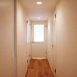 玄関からみた廊下部分。左側には二つのトイレと二つの個室の入り口。右は洗面所〜パントリーの入り口があります。